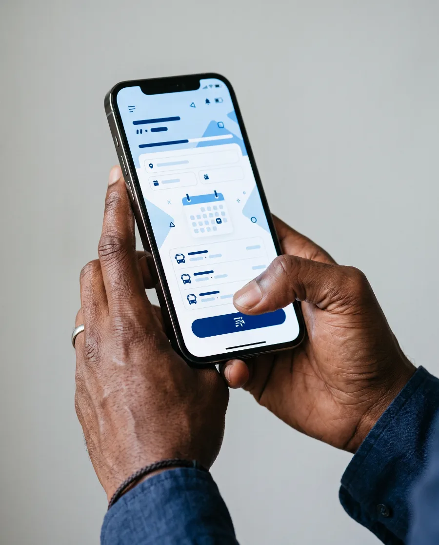 Hand holding a phone showing a bus booking app screen built in Kampala